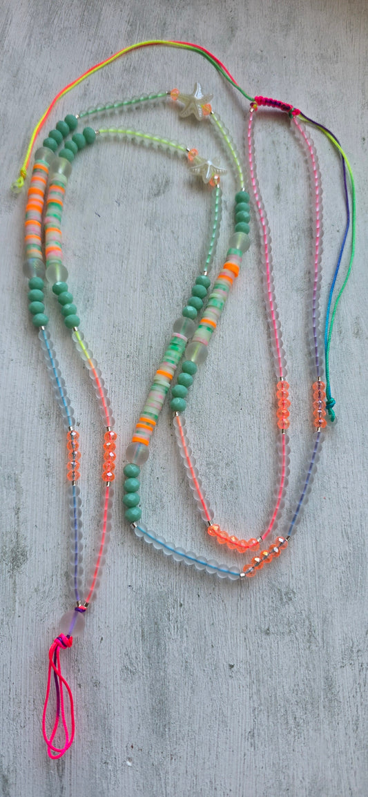 Colorful neon rainbow layered beaded necklace with star charms laid flat on a white surface
